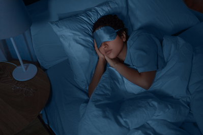 woman sleeping in a dark room while wearing an eye mask
