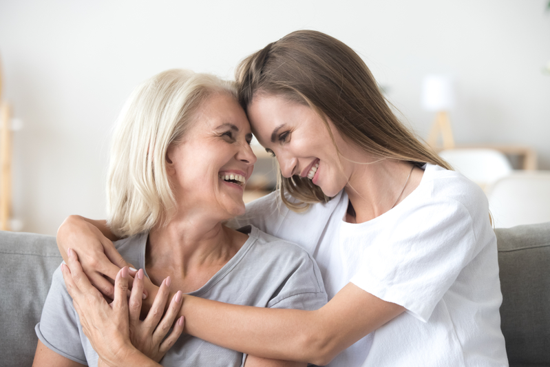 older mother and daughter laughing while hugging