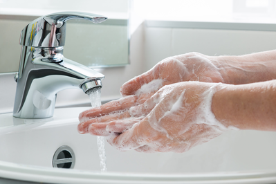 washing hands in white sink with soap and water
