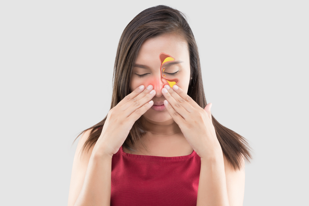 woman holding cheeks and nose with a diagram of sinus congestion overlayed on her face