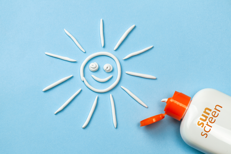 sunscreen bottle next to smiling sun made out of sunscreen