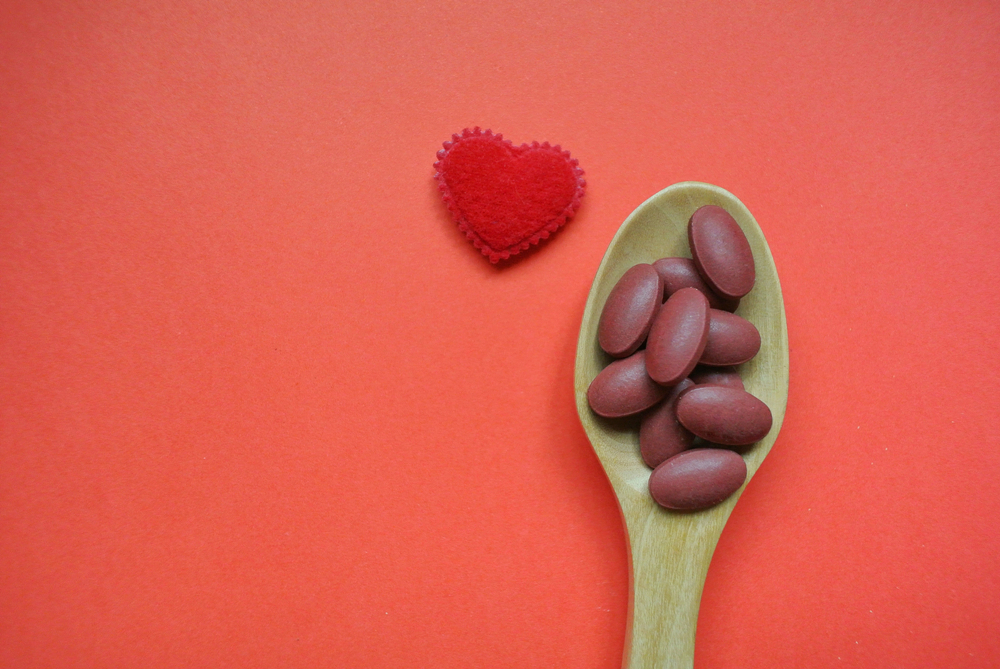 iron pills in spoon next to red heart