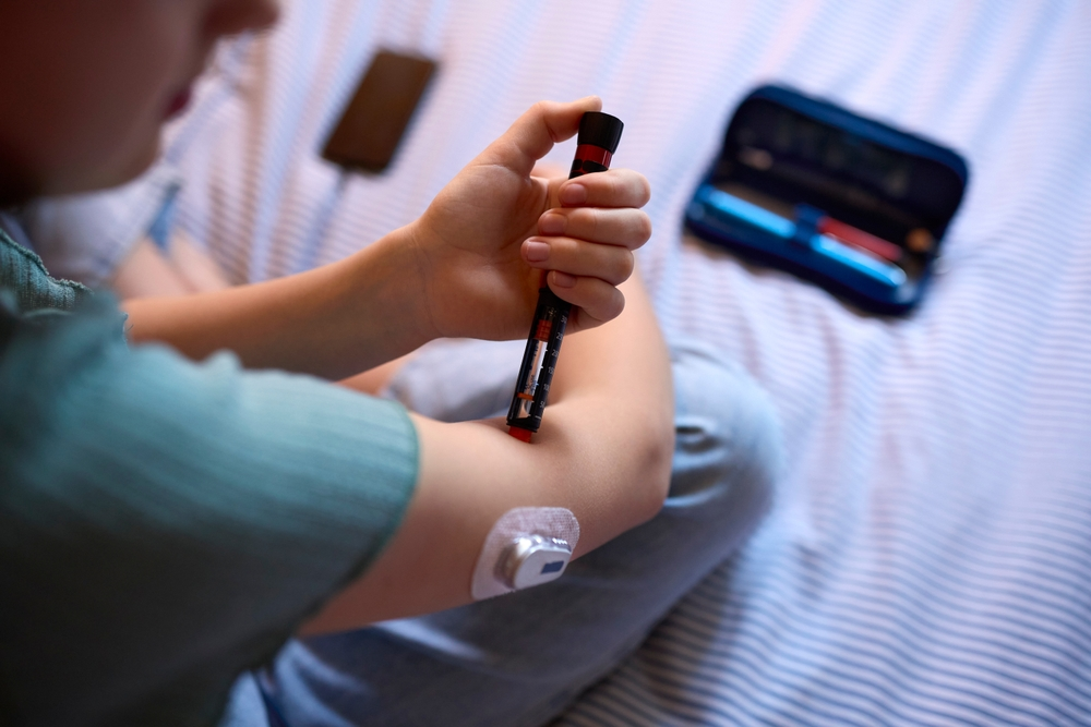 person with diabetes injecting insulin in arm with glucose monitor