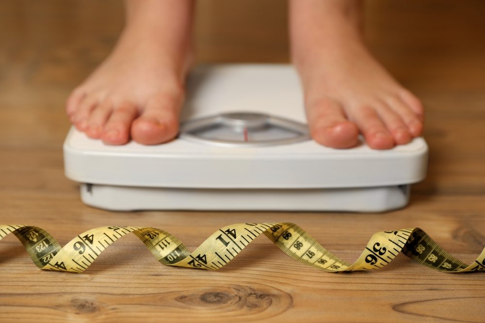 measuring tape in front of feet standing on floor scale