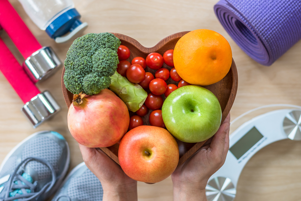 heart-shaped bowl of fruits and vegetables and exercise equipment