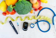 blood sugar monitor, insulin, stethoscope, and tape measure next to assorted  fruits and vegetables